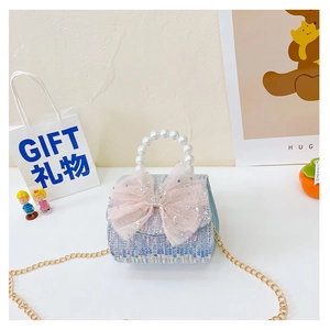 Detail of blue tweed girl bag featuring a large pink bow, pearl handle and crown charm