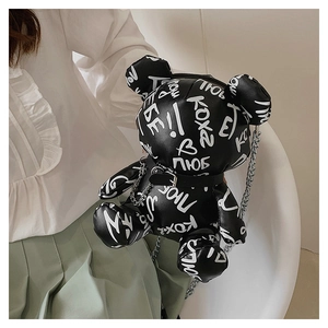 Detail of black teddy bear crossbody bag featuring white graffiti and silver chain strap