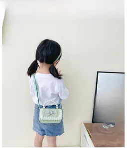 Rear view of a child wearing a light green lace crossbody bag with pearl handle and bow