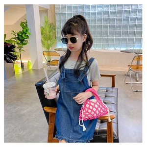 Detailed shot of kids pink hollow mesh woven bucket bag with cream inner pouch