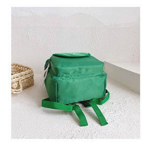 Detail view of green canvas backpack featuring adjustable straps and white logo lettering