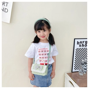 Close-up of green lace mini bag with pearl handle and rhinestone bow on a child model
