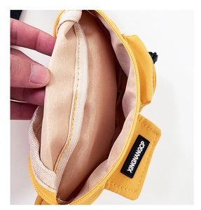 Vista dettagliata del marsupio giallo per bambini che mostra la fodera interna e la tasca velcro