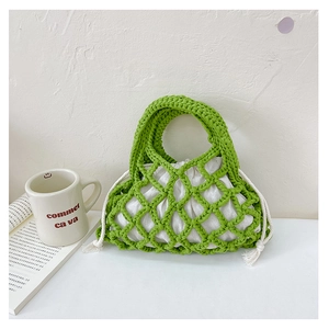 Detail of hand-woven green cotton net bag with white drawstring inner pouch on table