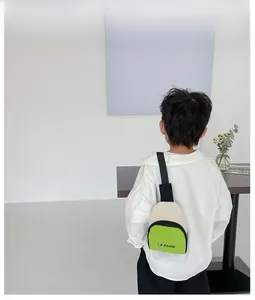 Vue arrière d'un enfant portant un sac de poitrine en toile verte et crème