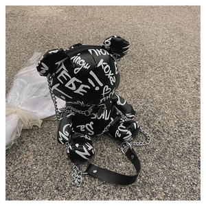 Detail of bear-shaped crossbody bag with white graffiti print and silver chain strap