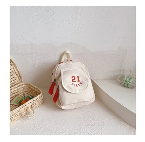 Detail of off-white canvas kids backpack featuring red 21 graphics and ribbon zipper pull