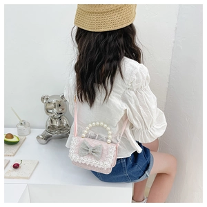 Detail of pink lace kids purse featuring pearl handle and sparkling rhinestone bow knot