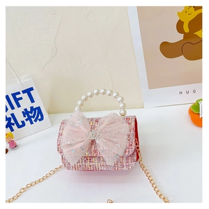 Close-up of pink tweed girl's handbag featuring mesh bow, crown pin and pearl handle