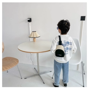 Vue arrière d'un enfant portant un sac de poitrine bicolore tendance dans un décor moderne