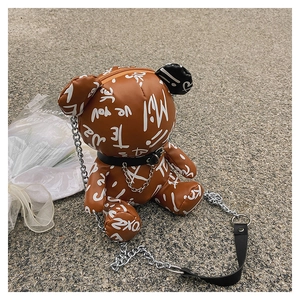 Detail of bear-shaped crossbody bag with graffiti print and silver chain strap