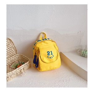 Detailed macro view of yellow canvas kids backpack with blue zipper and text print