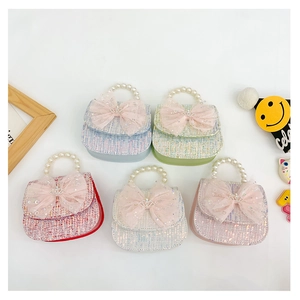 Detailed overhead view of mini tweed children bags with pearl handles and mesh bows