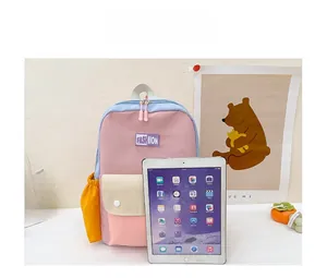 Kids color-block canvas backpack size comparison with a tablet in a soft light setting