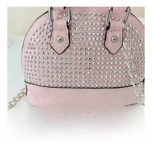 Close-up of pink suede girl's mini shell bag with sparkly rhinestones and metal handle