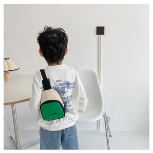 Vue détaillée de la sacoche enfant en toile vert et beige portée par un enfant mannequin