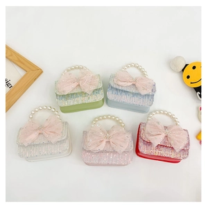 Detail of tweed girls' handbag with large mesh bow, crown ornament, and pearl handle in 5 colors