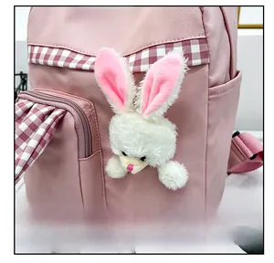 Close-up of pink nylon kids backpack featuring white plush rabbit and red plaid detail