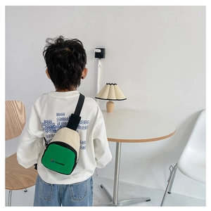 Sac de poitrine pour enfants vert et beige avec bandoulière réglable porté par un enfant