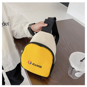 Détail du sac bandoulière enfant en toile jaune et beige avec lettres sur table en bois