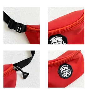 Macro detail of red nylon belt bag with black adjustable strap and circular fashion patch