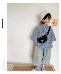 Detail of trendy kids blue plaid shirt and denim pants with a black crossbody bag