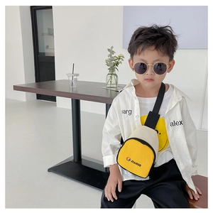 Détail d'un sac de poitrine enfant en toile jaune et beige avec sangle noire ajustable
