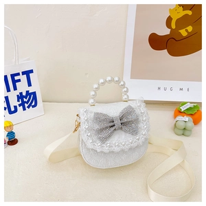 Detail of white lace edges, rhinestone bow and pearl handle on girls cross-body bag