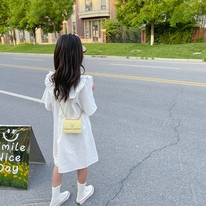 Fillette en robe blanche portant un mini sac à bandoulière matelassé jaune, vue extérieure