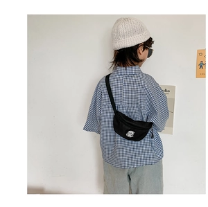 Kid's black canvas waist bag with round logo patch shown on a stylish toddler model