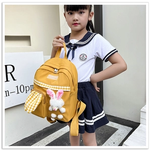 Detail of yellow toddler backpack with plush rabbit and checkered strap on a child