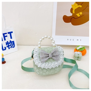 Detail of green child handbag with pearl handle, lace trim and rhinestone bow decoration