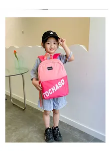 Vue détaillée d'une fille portant un sac à dos en toile rose avec inscription TOCHASO