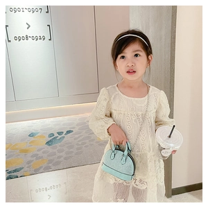 Toddler girl modeling light blue shell purse with silver chain and woven texture details