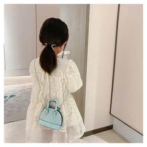 Girl wearing a light blue shell bag with sparkling rhinestones and metal chain strap