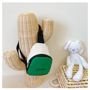 Détail d'un sac de poitrine en toile vert et beige pour enfant avec poche zippée
