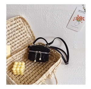 Gros plan d'un mini sac cylindre en strass avec pendentif perle dans un panier