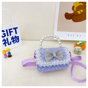 Detail view of purple kids handbag with pearl handle, lace trim, and rhinestone bow accessory