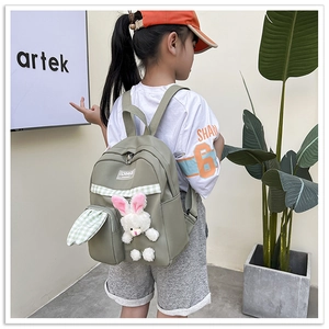 Detail view of green canvas kids backpack with cute plush bunny pendant and plaid trim