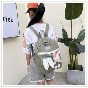 Detail of green kids backpack with cute plush rabbit charm and grid pattern design