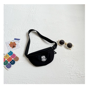 Detail of black nylon kids chest bag with fashion patch and adjustable strap