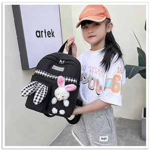 Close-up of black canvas kids backpack featuring a plush bunny doll and checkered ribbon detail