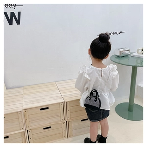Toddler girl modeling a black and white sequin shell bag with a metal chain strap
