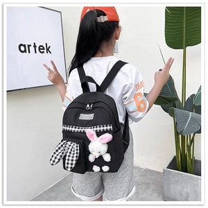 Close-up of kids black backpack with white plush bunny and checkered ear details