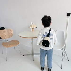 Sac de poitrine enfant bicolore avec logo JIANCE porté par un garçon dans un salon