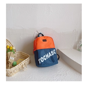 Gros plan d'un sac à dos en toile orange et marine avec logo TOCHASO sur fond texturé