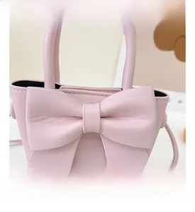 Close-up of a pink PU leather handbag featuring a large bow detail and elegant handle