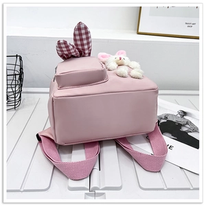 Detail showing pink rabbit ears backpack with plush bunny charm and zip pocket