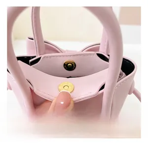 Detail of pink PU leather mini handbag with gold magnetic closure and bow accent