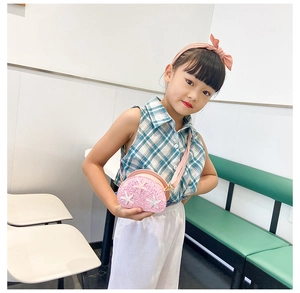 Pink sequin shell crossbody bag with starfish detail shown on a young girl in a cafe